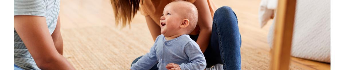 Baby on wood floor laughing with parents