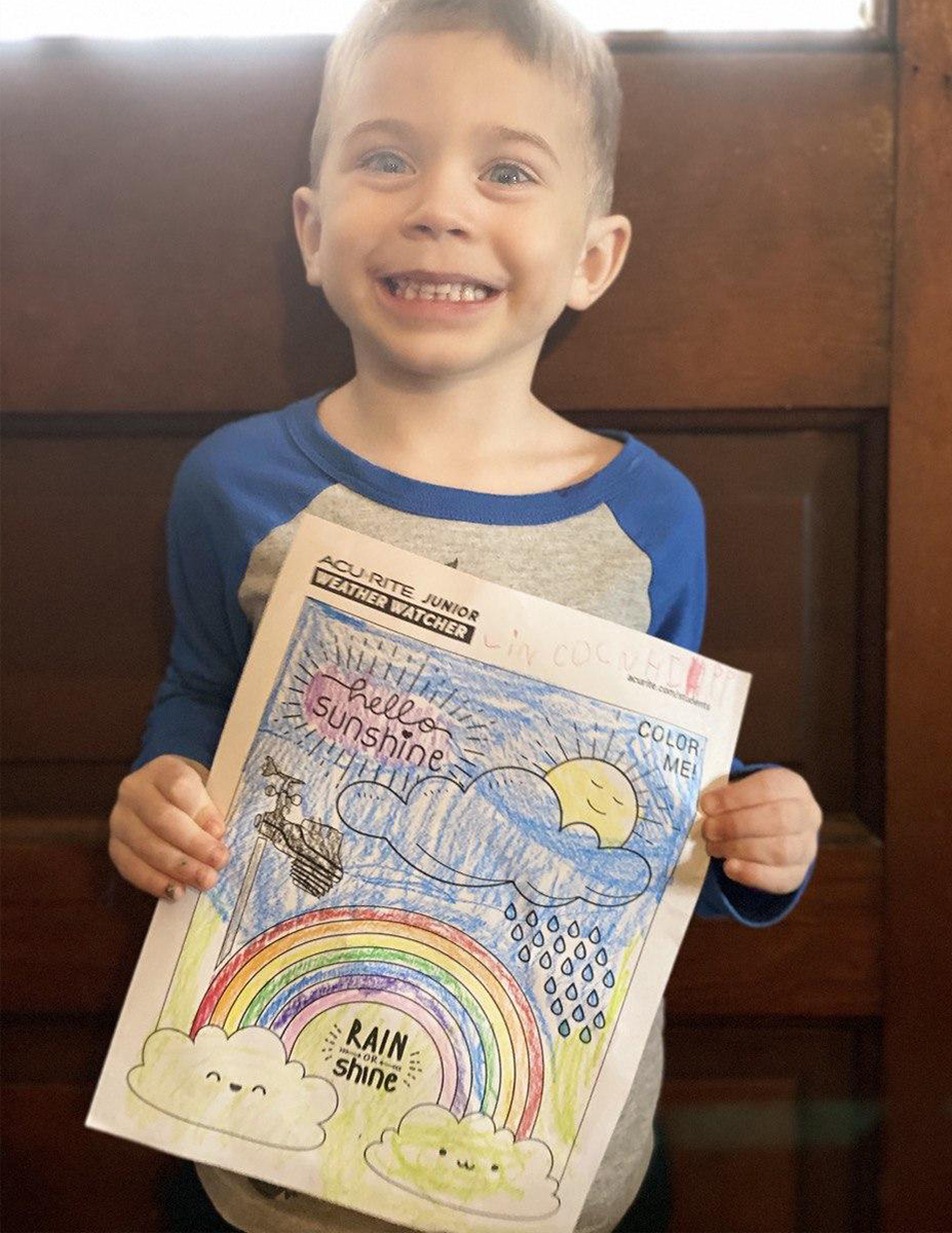 Boy holding coloring page in front of door