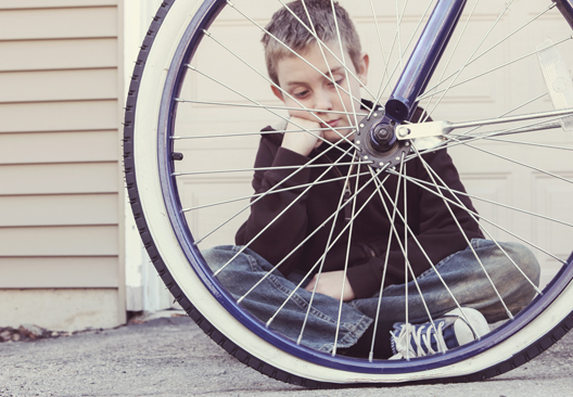 Child looking at flat tire of bicycle